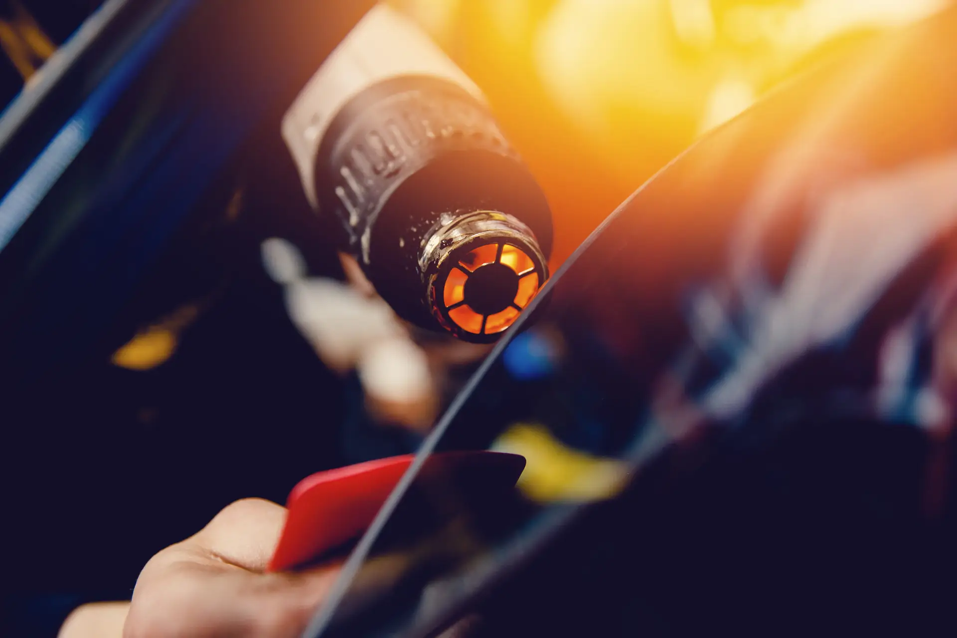 installer of tinted film for the car glass with a hairdryer and spatula